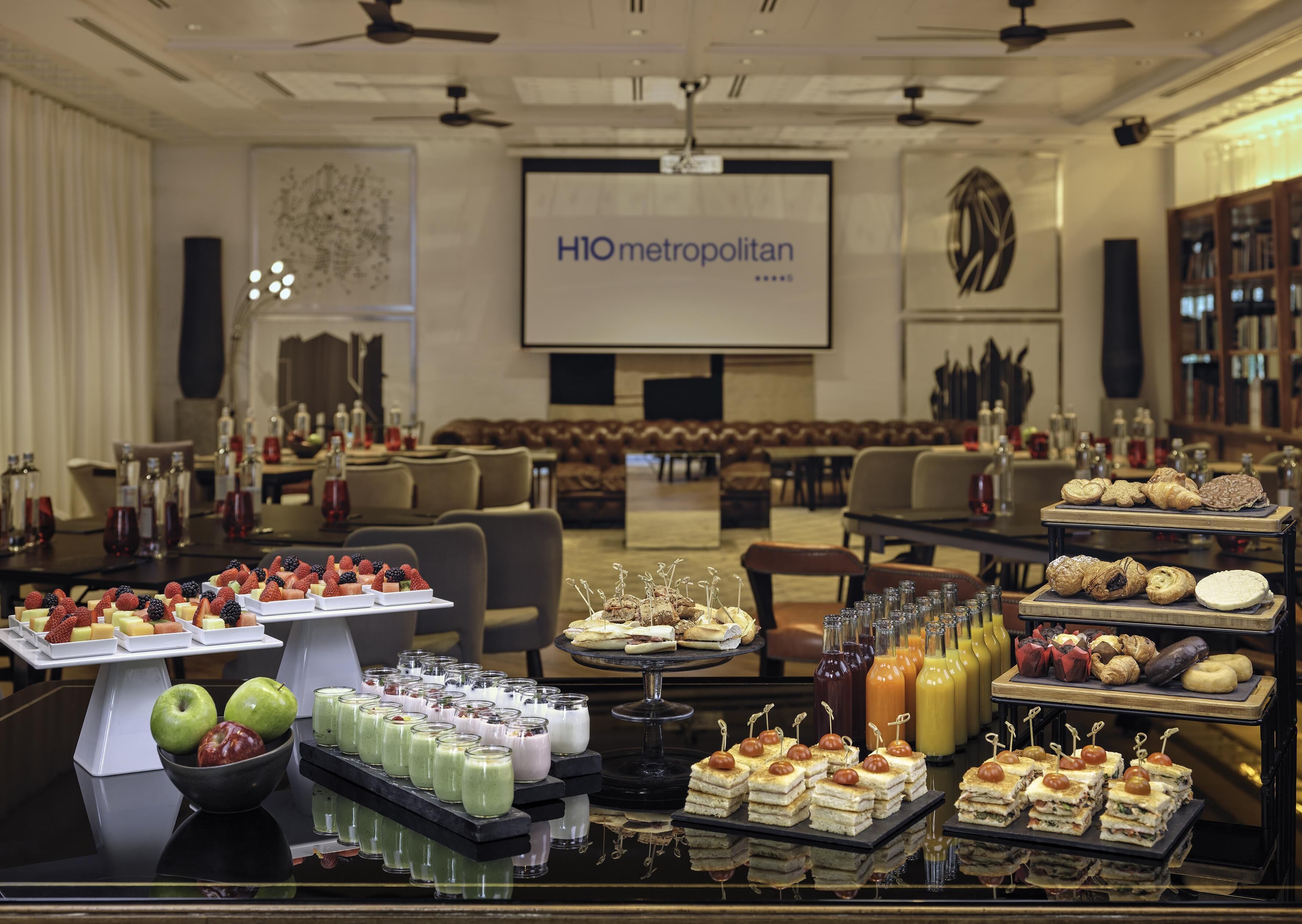 A buffet with various food items and a projection screen in the background.