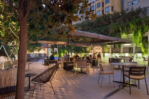 Ein Terrassenbereich im Freien mit Sitzgelegenheiten, Tischen und einem überdachten Bereich.