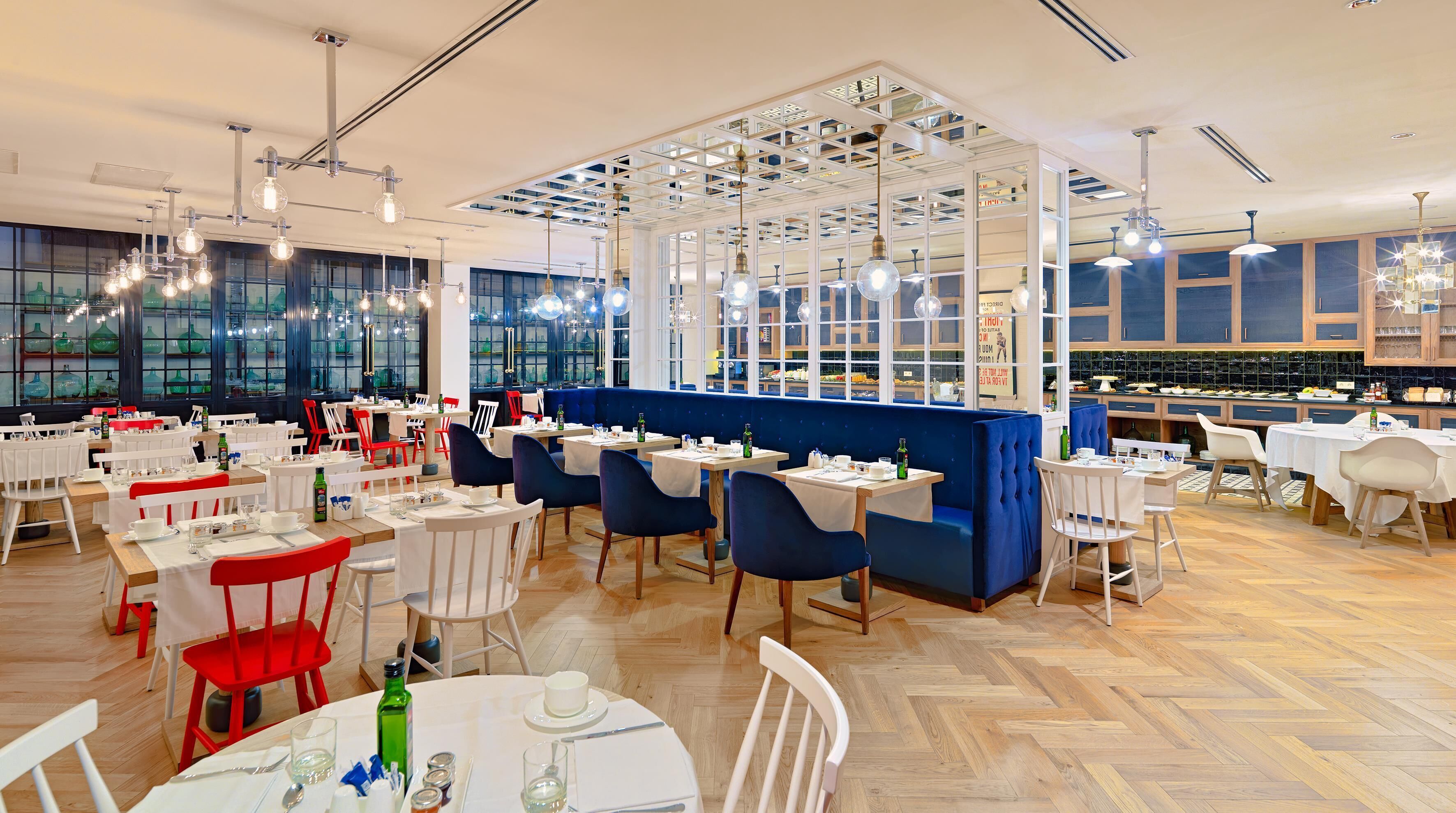 Un restaurante espacioso con techos altos, iluminación moderna y una variedad de opciones de asientos, incluyendo mesas y cabinas.