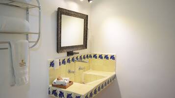 A bathroom with a sink, mirror, towel rack, and a shelf with towels.