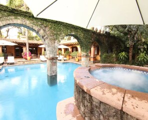 Una piscina al aire libre, sombrillas, sillones reclinables de piscina