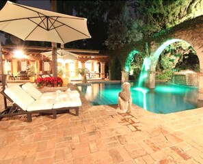 Una piscina al aire libre, sombrillas, sillones reclinables de piscina