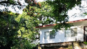 A two-story house with a brick exterior, a wooden staircase, and a lush garden. - Hotel Boutique La Joyita (Cuernavaca)