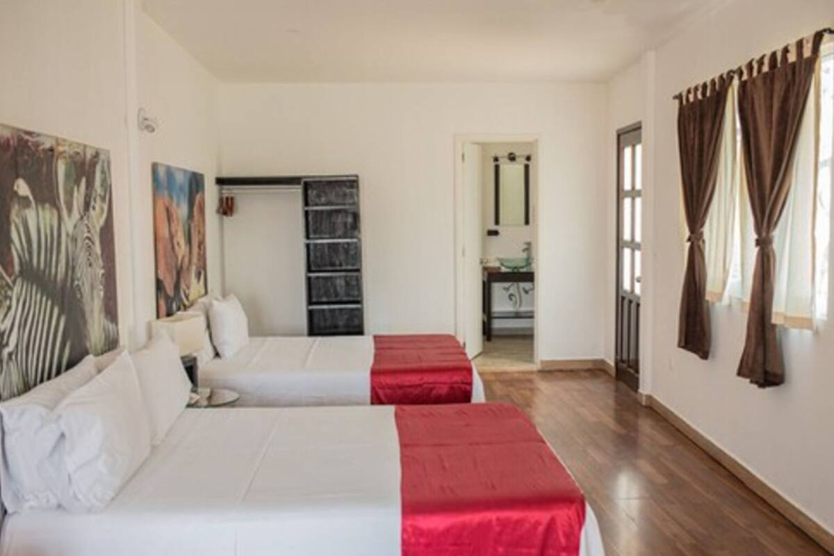 A hotel room with two beds, a bathroom, and a view of the outside.