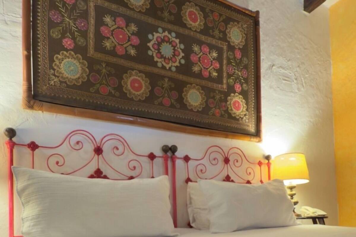 A bed with a red metal headboard, white pillows, and a brown blanket.