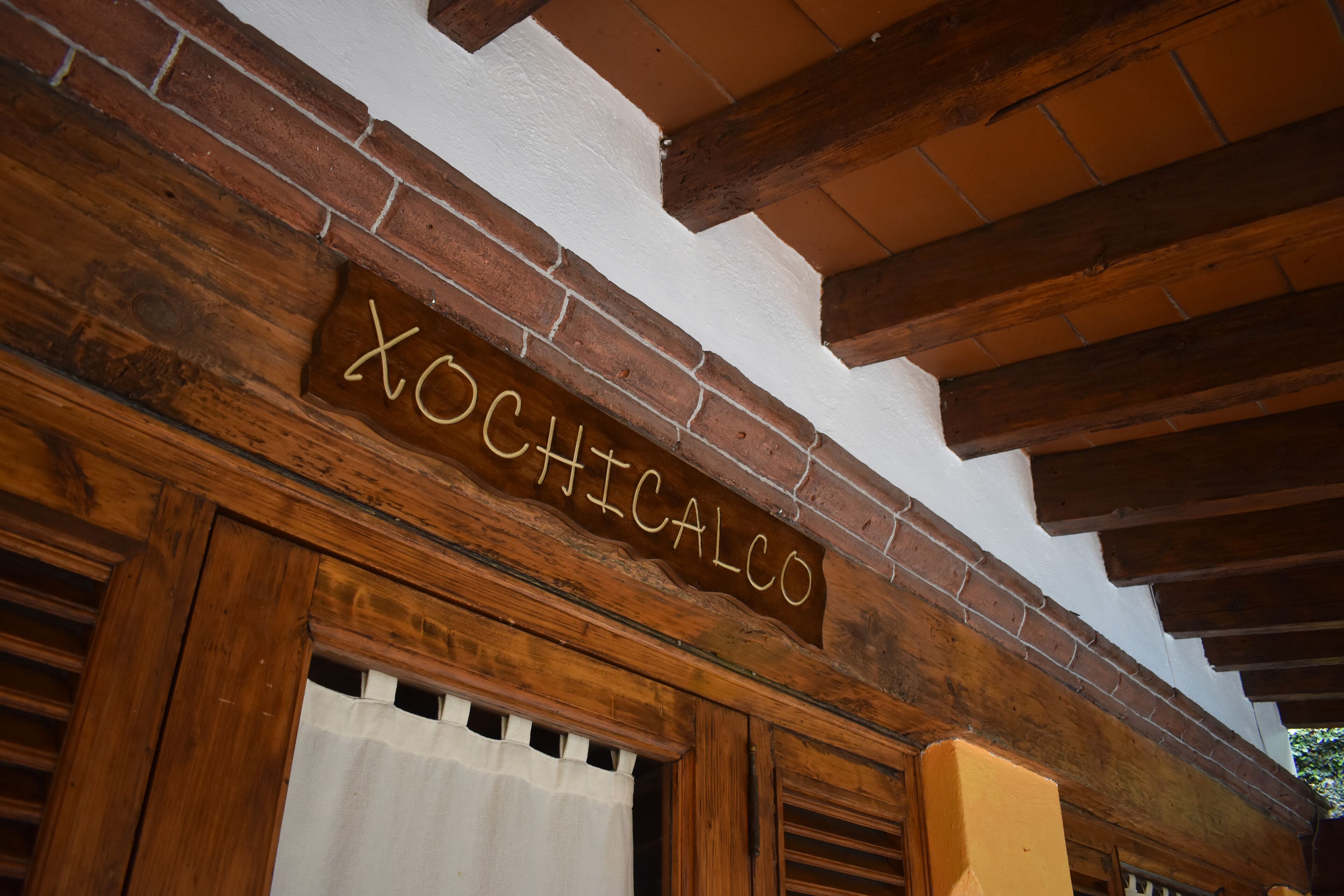 Un letrero de madera con el nombre 'XOCHICALCO' sobre un vano de puerta.