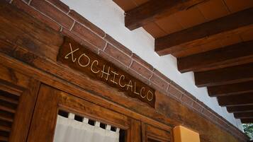 Un letrero de madera con el nombre 'XOCHICALCO' sobre un vano de puerta.