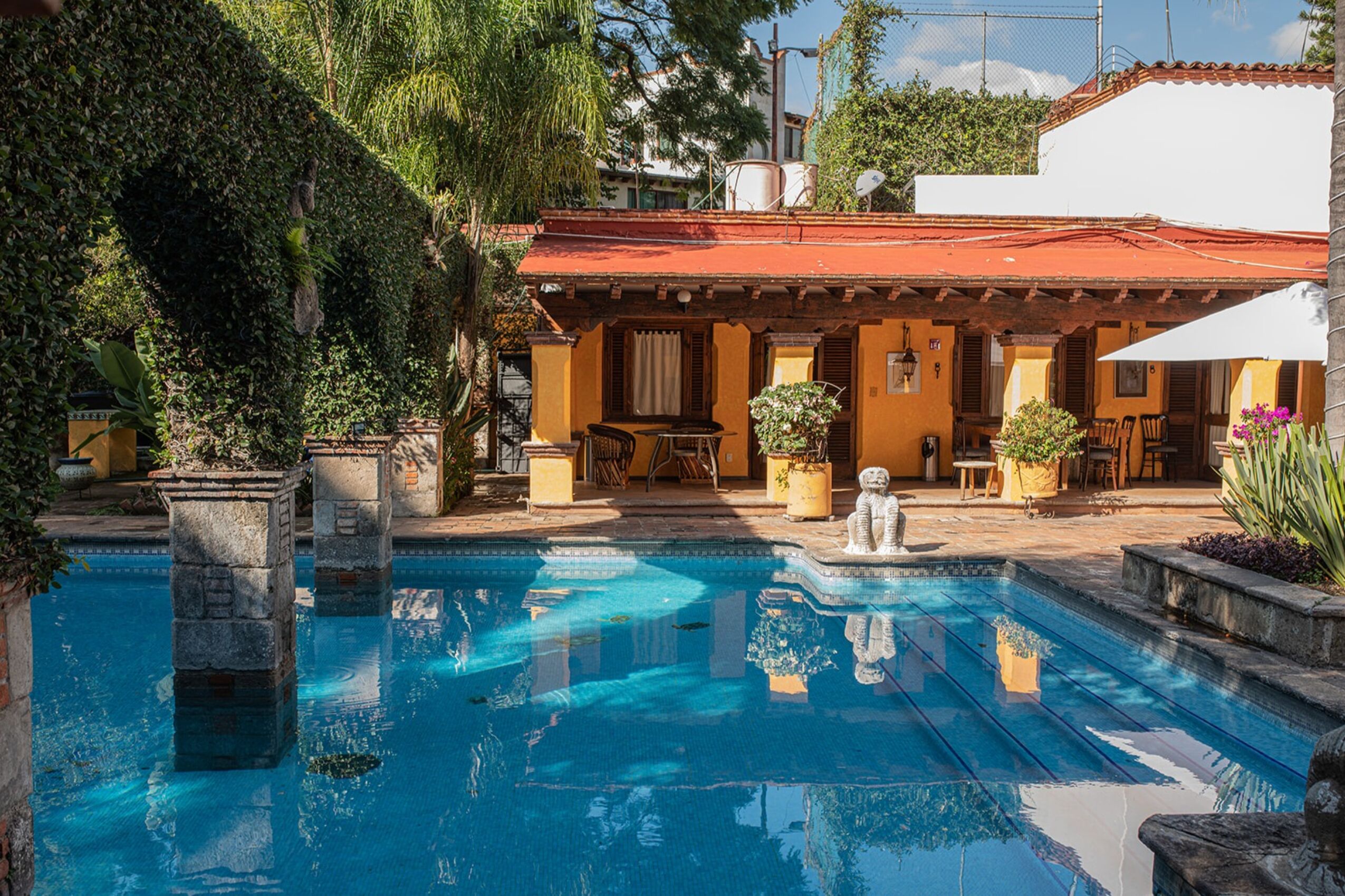 Un área de piscina con pilares de piedra, una fuente y mobiliario exterior.