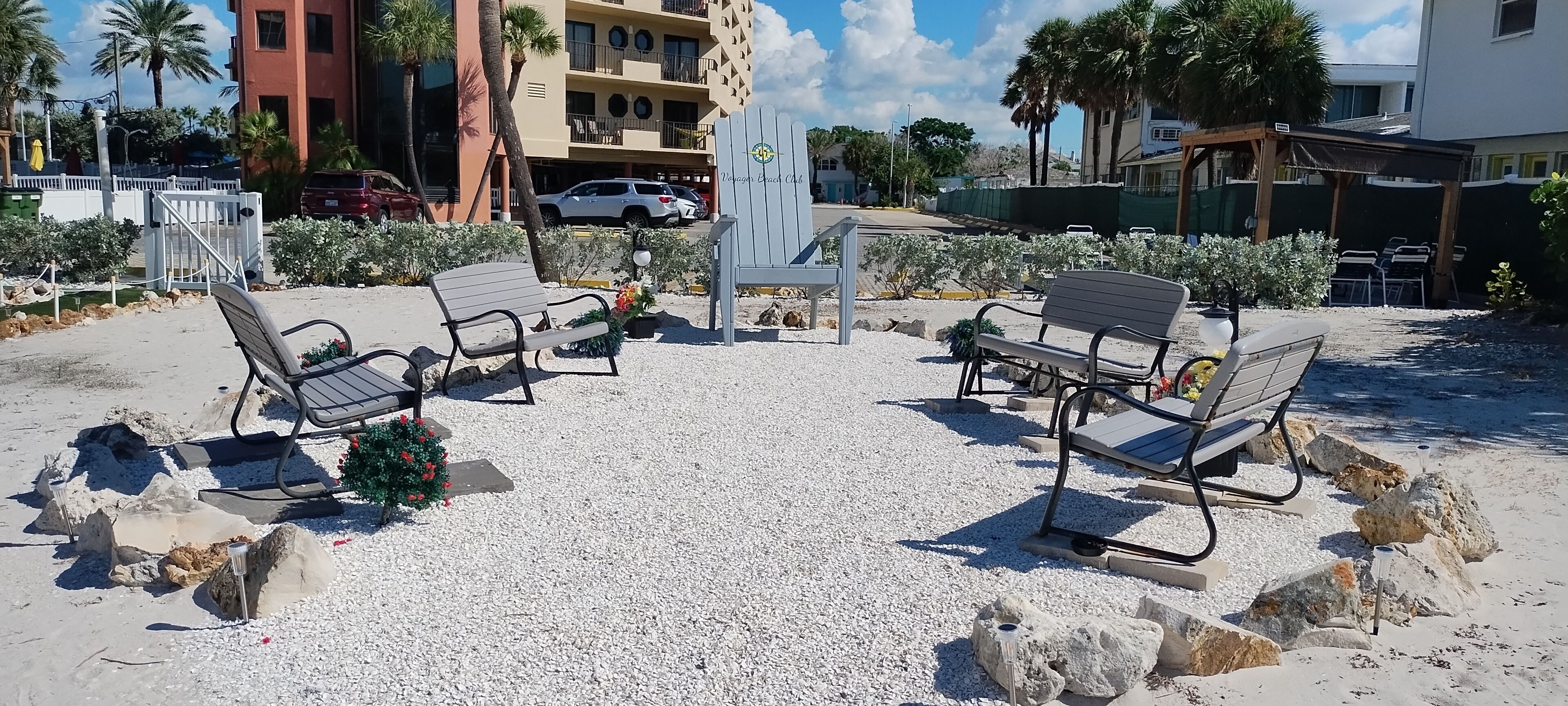 Un espacio al aire libre con bancos y una fuente decorativa, rodeado de grava y rocas.