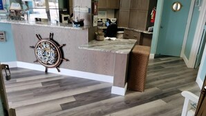 A kitchen with a wooden island, a ship's wheel decoration, and a tiled floor.