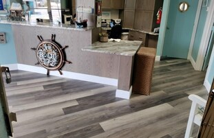 A kitchen with a wooden island, a ship's wheel decoration, and a tiled floor.
