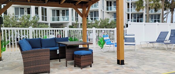 Un patio al aire libre con mobiliario de mimbre, una mesa y sillas.