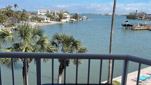 A balcony with a view of a marina, palm trees, and a calm body of water.