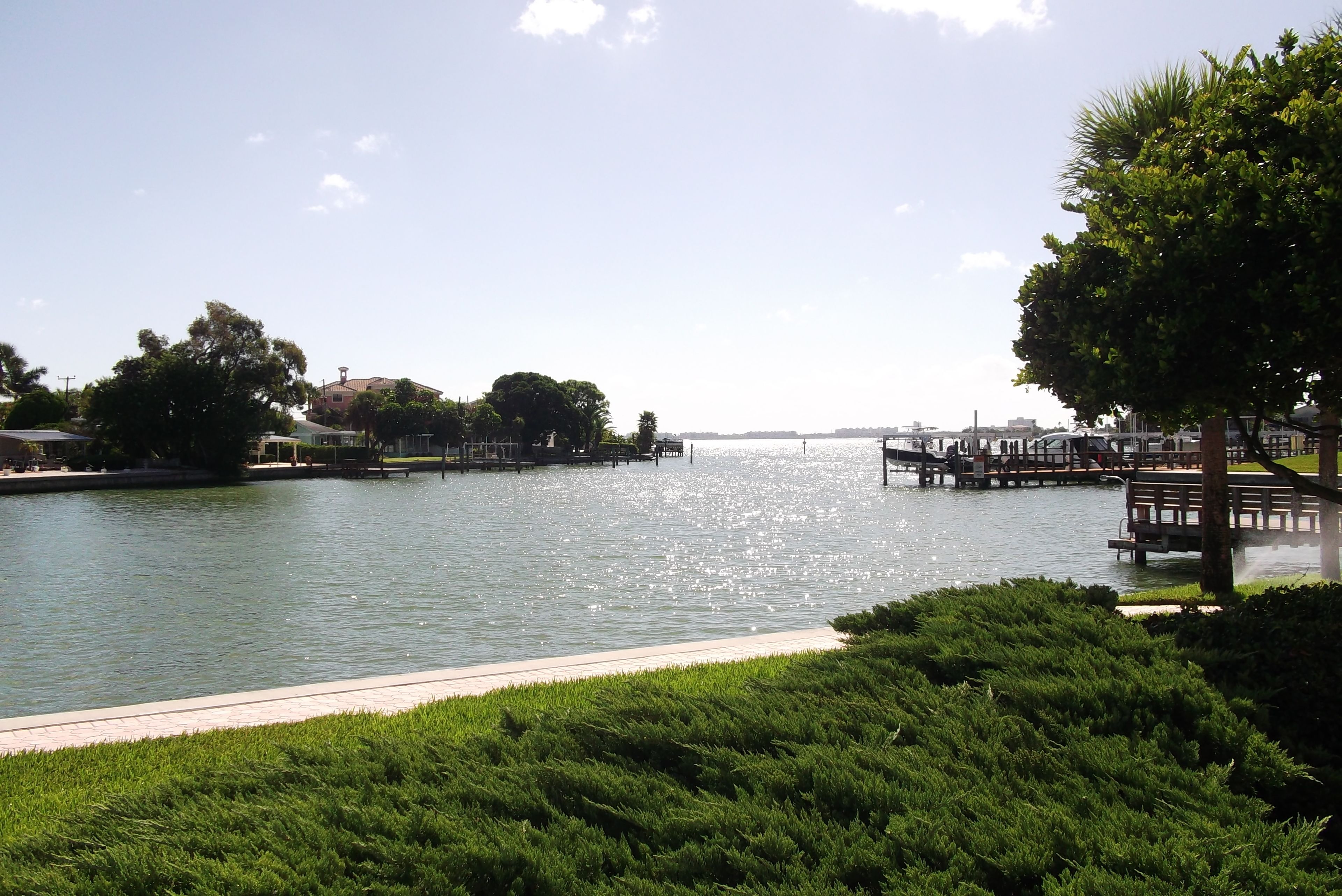 A waterfront park with a walking path, benches, and a dock extending into the water.