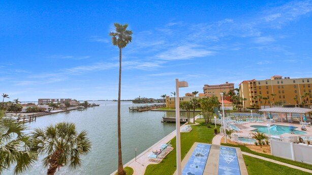 A resort with a pool area, palm trees, and a view of the water.