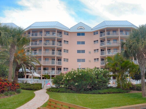 A multi-story hotel with balconies, a central courtyard, and surrounding greenery. - Sunrise Resort by Liberté (St. Pete Beach)