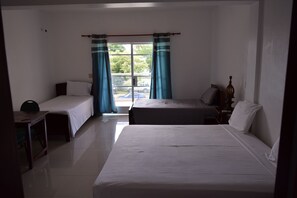A hotel room with two single beds, a desk with a chair, a nightstand with a lamp, and a window with curtains. - Auberge du Rayon Vert (Port-Salut)