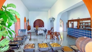 A buffet setup with various food items, a wooden barrel, and a tiled wall. - Hotel du Village (Port-Salut)