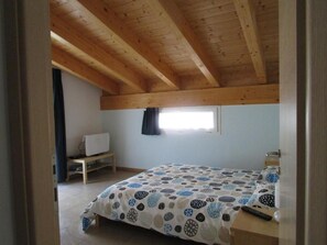 A bedroom with a wooden ceiling, a bed with a patterned bedspread, a small window, and a bedside table. - B&B Sibi (Lierna)