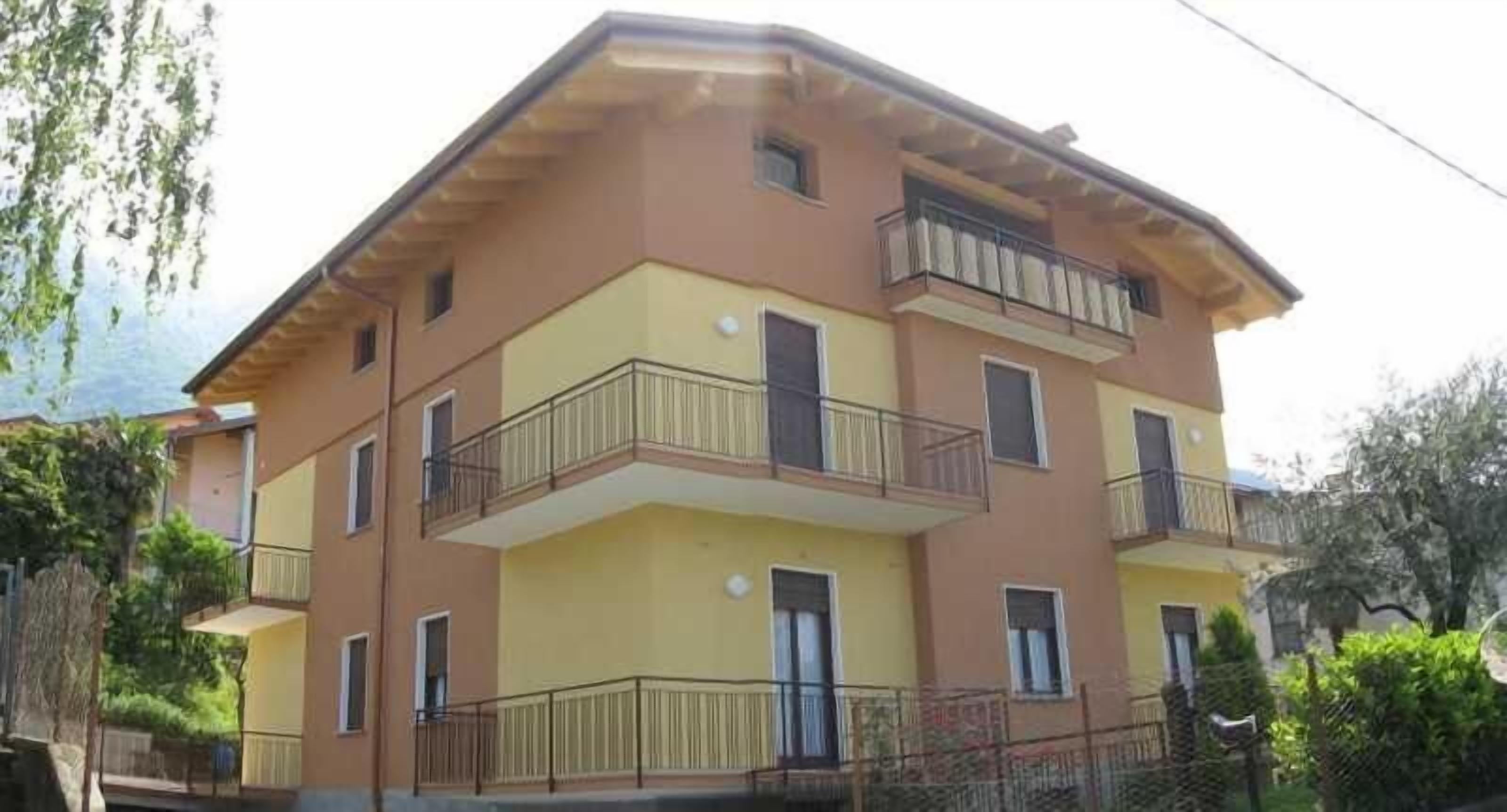 Un edificio residencial de varios pisos con balcones, techo plano y fachada amarilla.