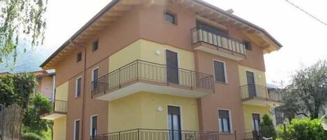 Un edificio residencial de varios pisos con balcones, techo plano y fachada amarilla.