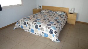 Une chambre à coucher avec un lit, deux tables de chevet, une fenêtre et un plafond en bois.