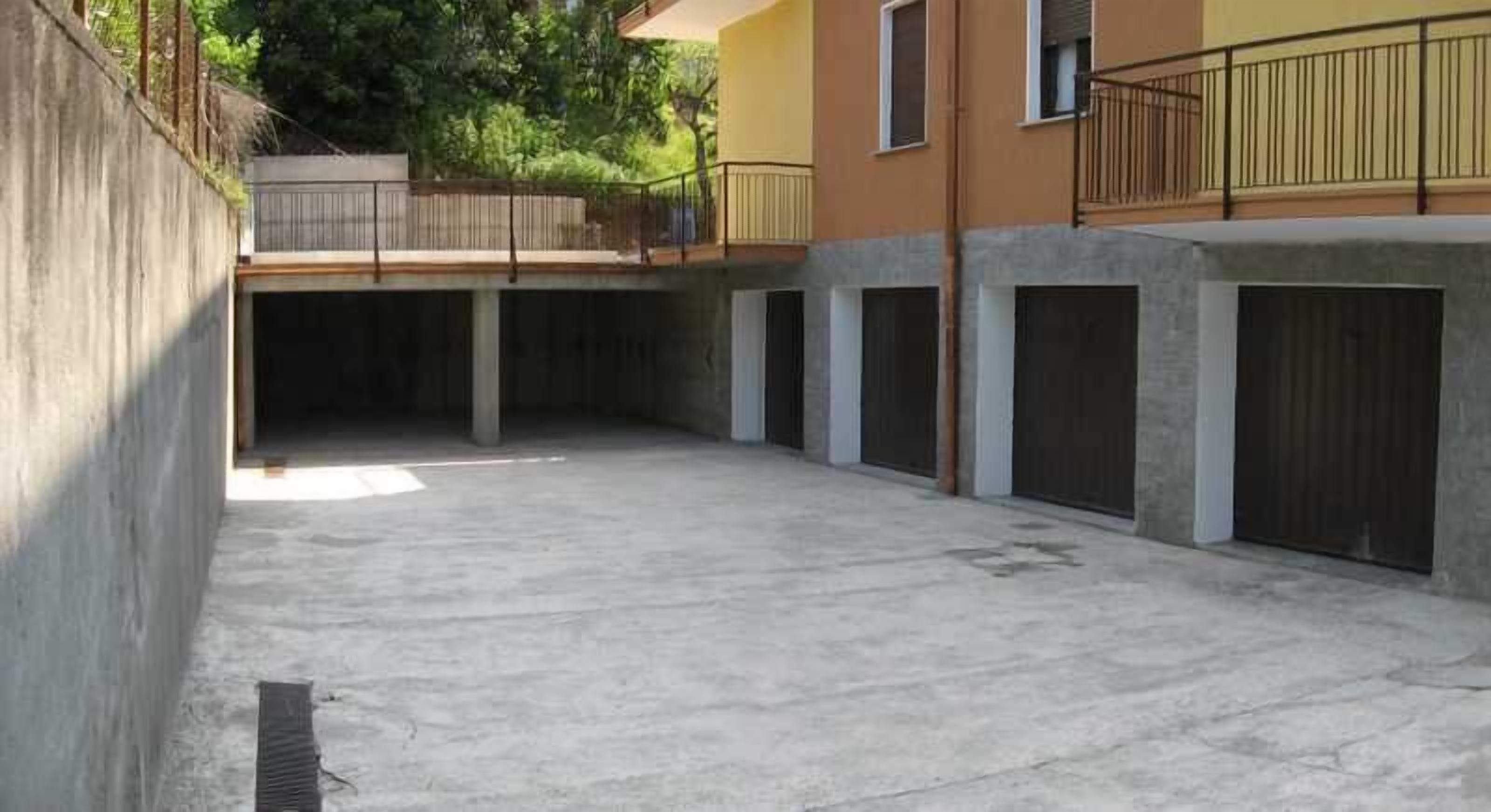 A concrete courtyard with a central open space, surrounded by buildings with balconies and garage doors.