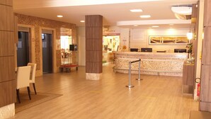 A hotel lobby with a reception desk, seating area, and a patterned floor.