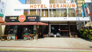 A multi-story hotel named Hotel Geranium with a prominent entrance and a visible sign.