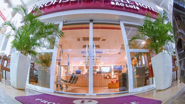 The entrance of the Professionalalle Hotel in São Luís with a reception desk, glass doors, and a purple doormat. - Profissionalle Hotel São Luís (São Luís)
