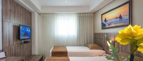 Habitación de hotel con dos camas, un televisor, un cuadro y un ventanal con cortinas.