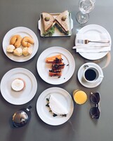 Una mesa con diferentes opciones de desayuno, como sándwiches, pasteles y bebidas.