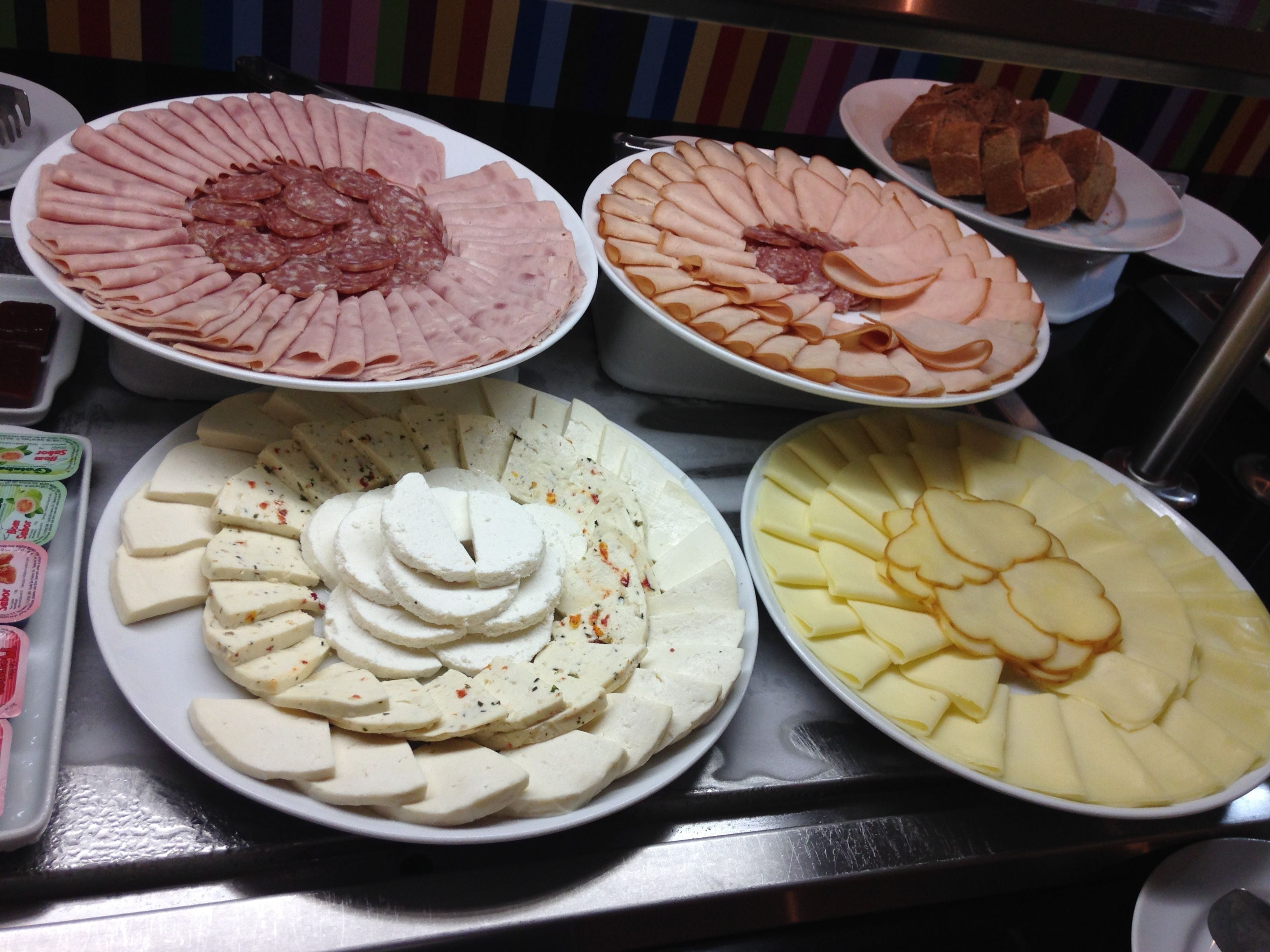 A buffet with various food items including sliced meats, cheeses, and other dishes.