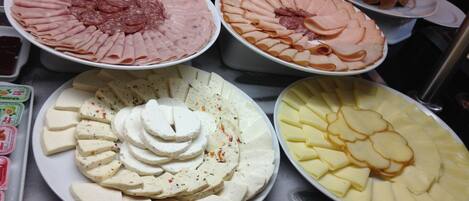 A buffet with various food items including sliced meats, cheeses, and other dishes.