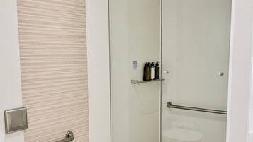 A modern bathroom with a glass shower enclosure, a toilet, and a sink.