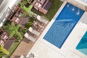 Una piscina al aire libre, sombrillas, tumbonas