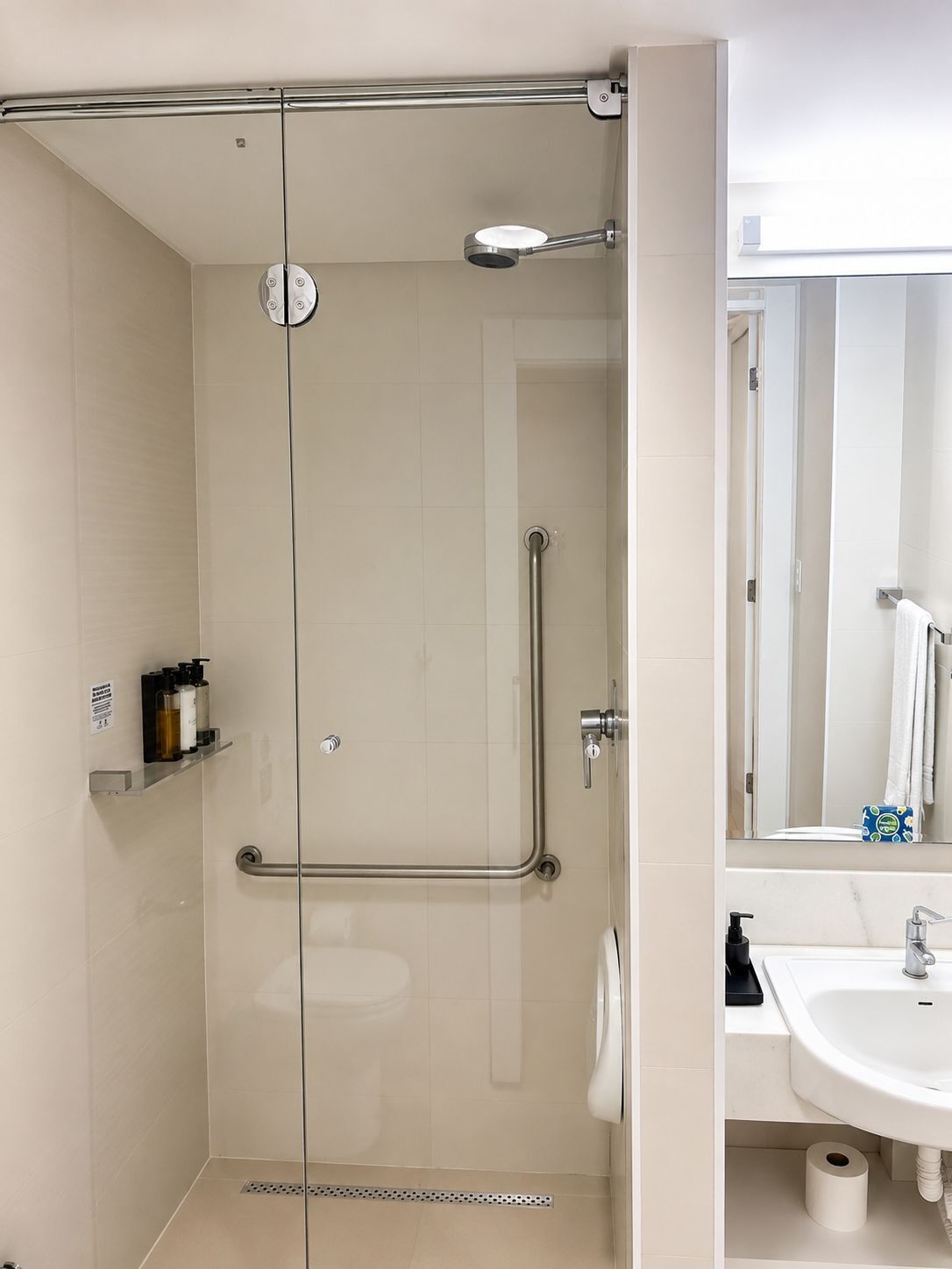 Un bagno moderno con doccia vetrata, lavandino bianco e specchio.