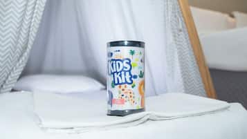 A bed with a white sheet and a metal container labeled "Kids Kit" on it.