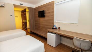 A hotel room with two beds, a desk with a computer, a TV, and a small fridge.