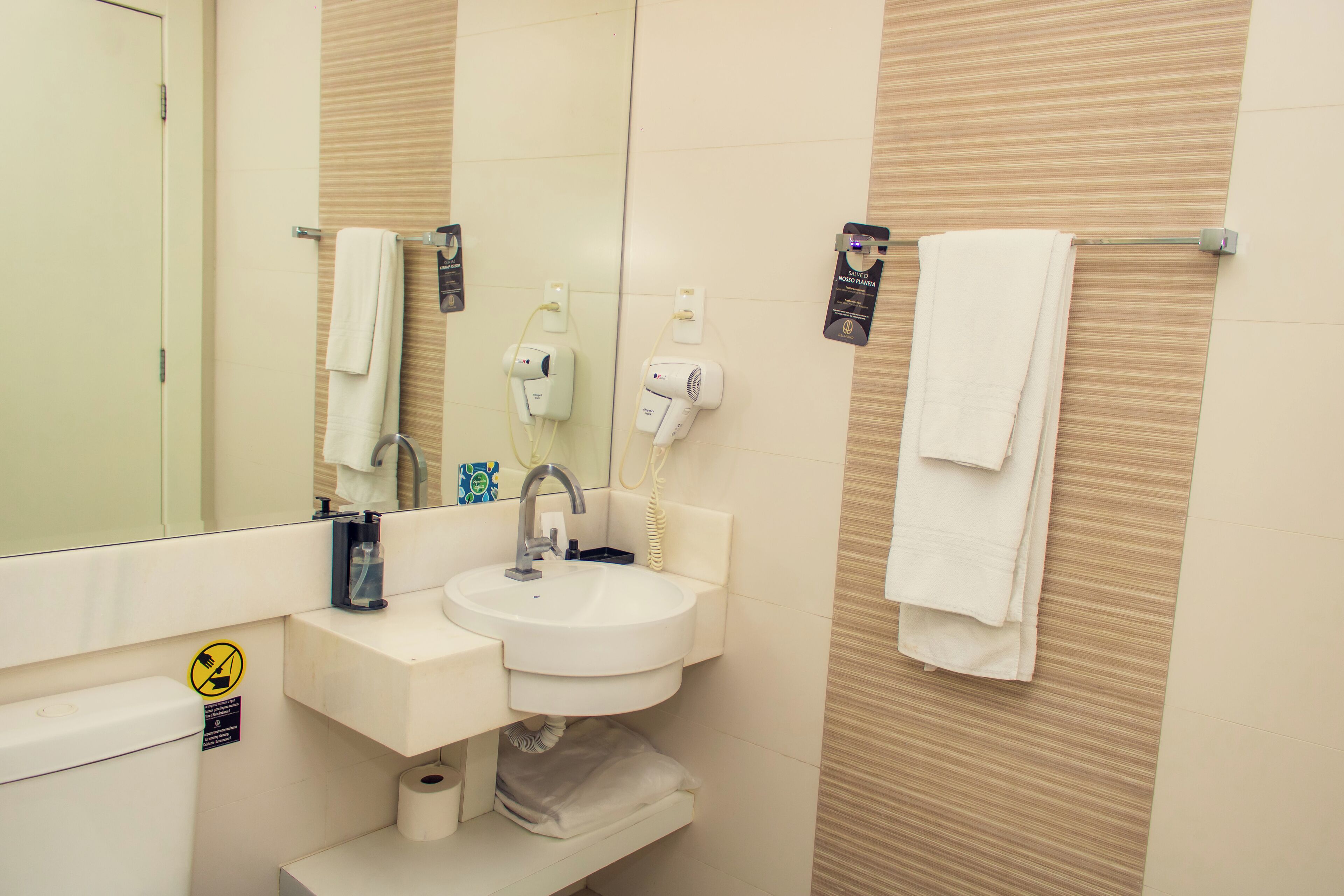 A bathroom with a sink, mirror, towel rack, and a toilet.