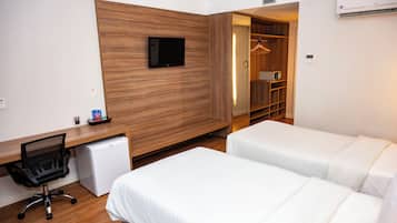 Habitació d'hotel amb paret d'accent de fusta, televisió de pantalla plana, escriptori amb ordinador, nevera petita i dos llits.