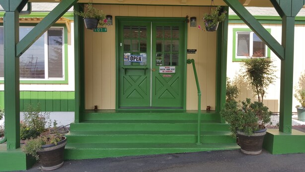 A green building with a '101 B' address sign, a 'VISA' sign, and a 'NO SOLICITORS' sign. - Safari Inn (Winston)