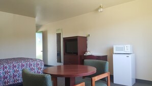 A hotel room with a bed, a desk with a chair, a television, a microwave, and a refrigerator. - Safari Inn (Winston)