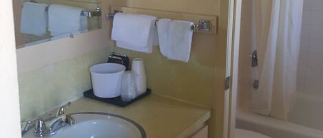 Un baño con lavamanos, espejo, toallero y cortina de ducha.