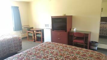 Une chambre d’hôtel avec deux lits, un bureau avec une télévision, un four à micro-ondes et un téléphone.