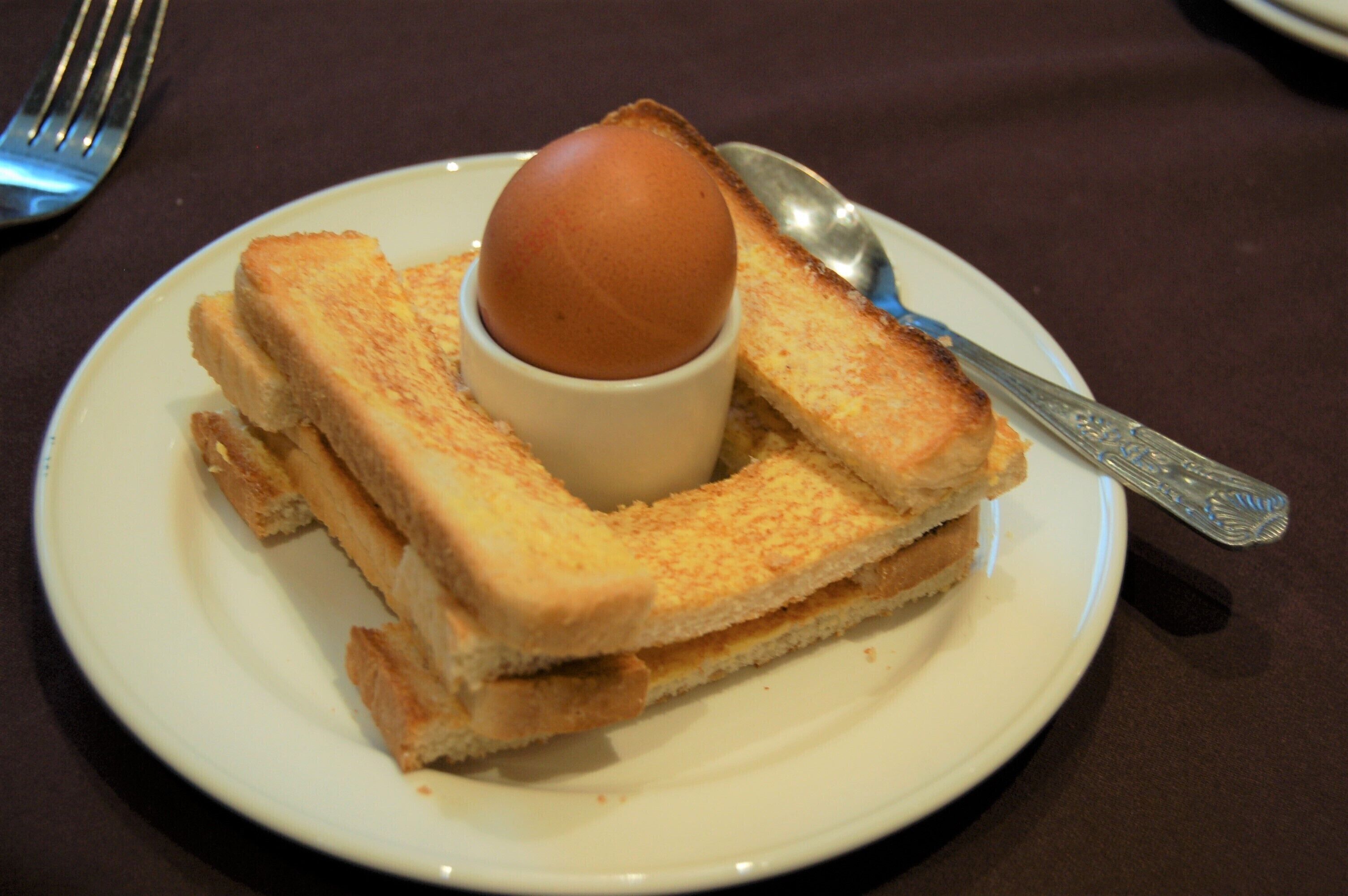 A plate with a sandwich and a boiled egg.
