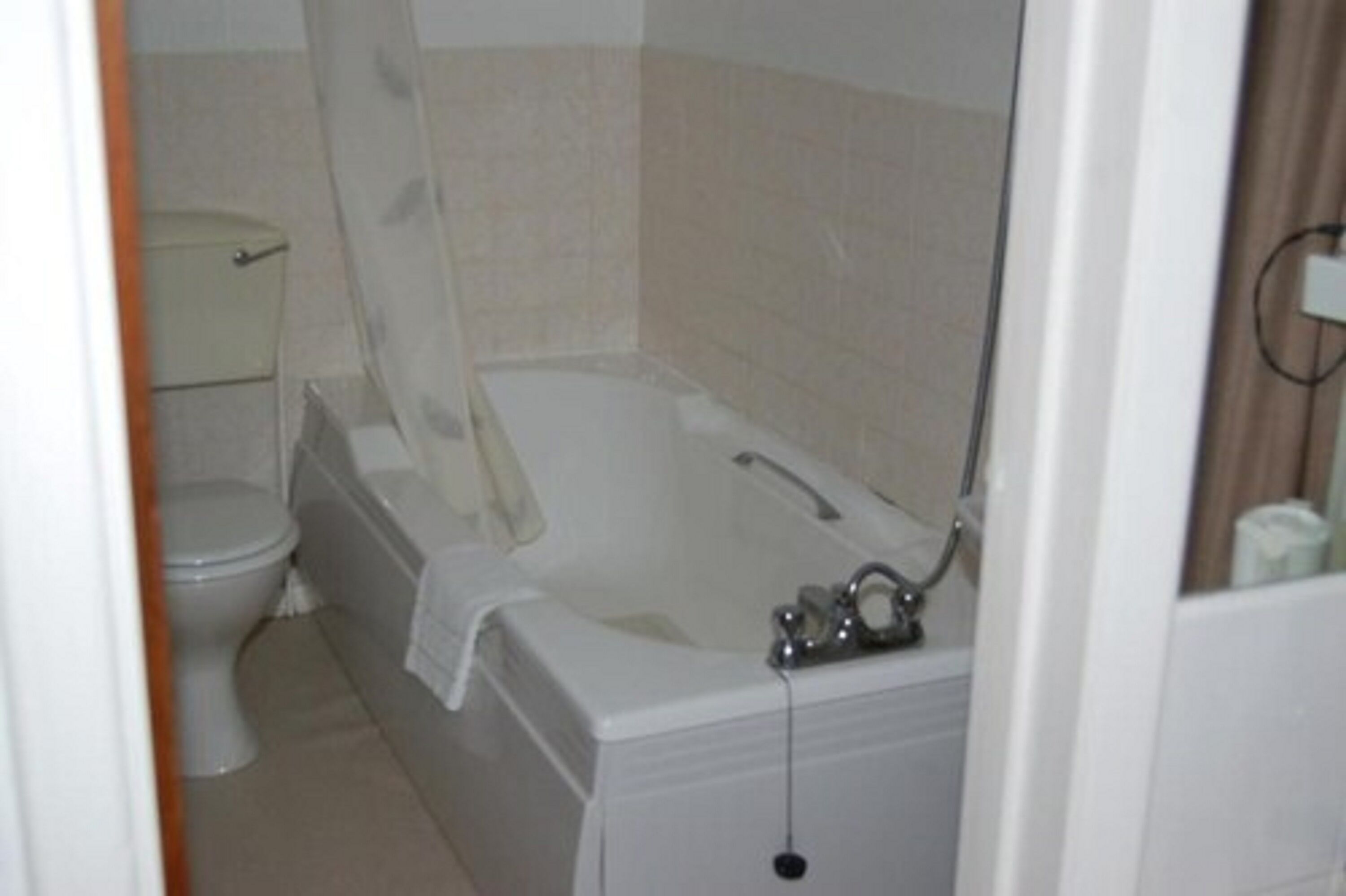 A bathroom with a bathtub, toilet, and shower curtain.