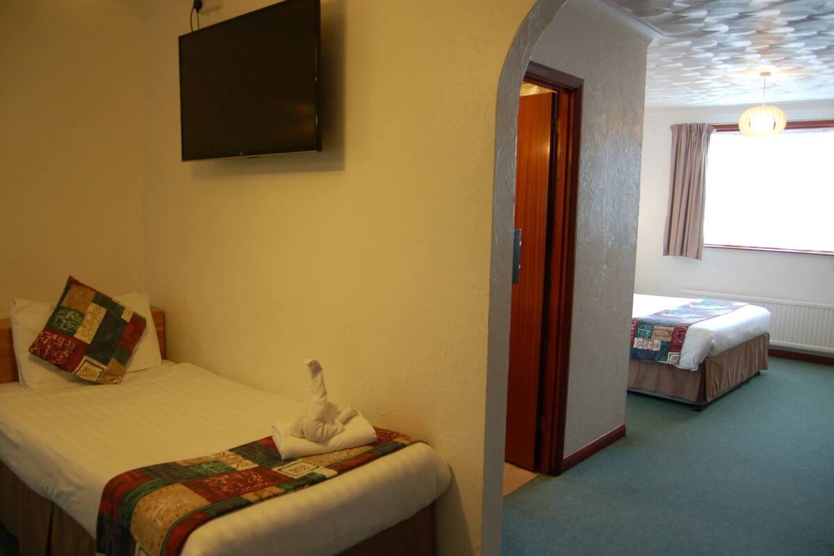 A hotel room with a bed, a TV mounted on the wall, and a window with curtains.