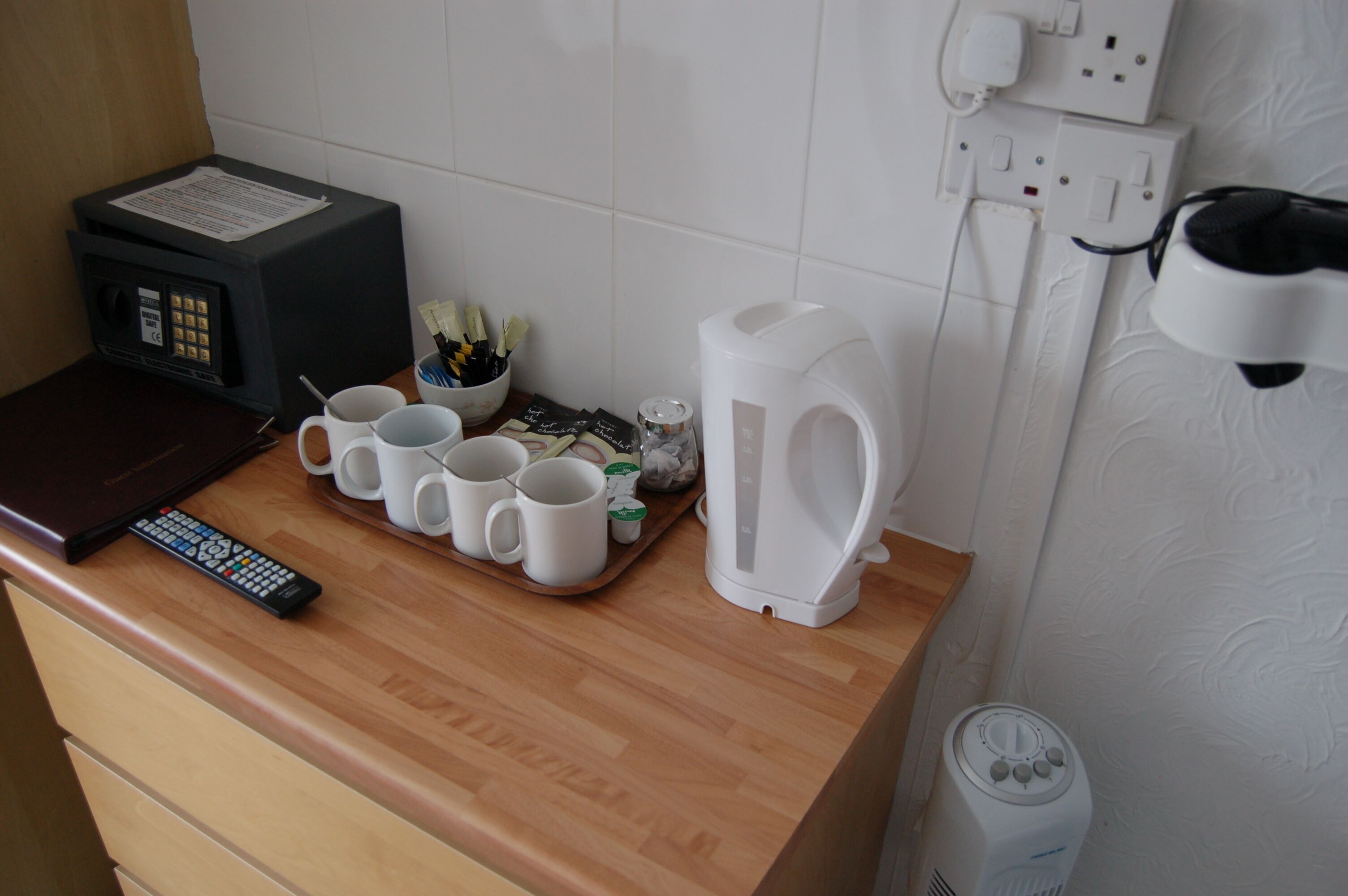 A kitchen counter with a microwave, a coffee maker, and a tray with mugs and utensils.
