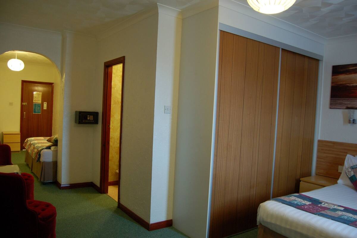 A hotel room with a bed, a desk, a chair, and a wardrobe.
